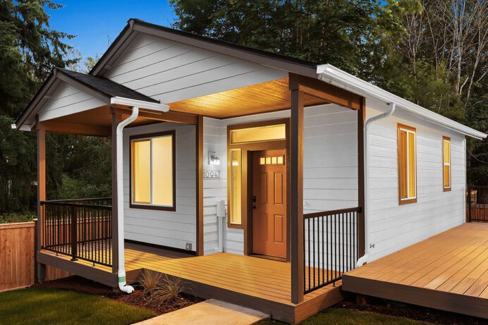 An ADU with multiple porches in craftsman style with the lights illuminating from within.