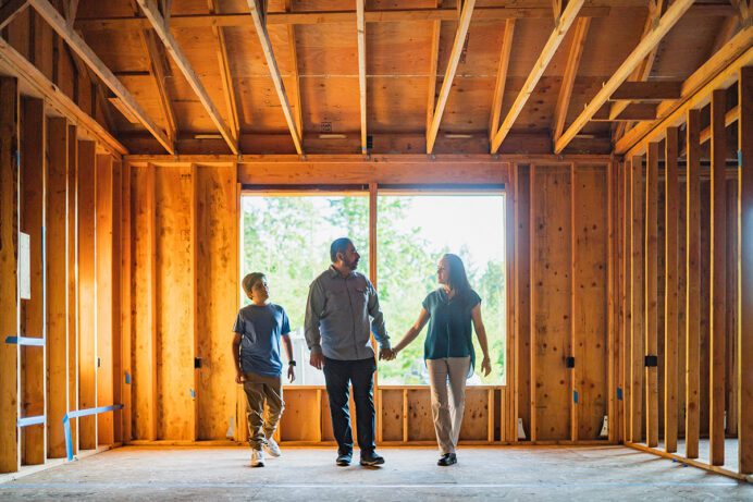 A family standing in the framework of their new home.